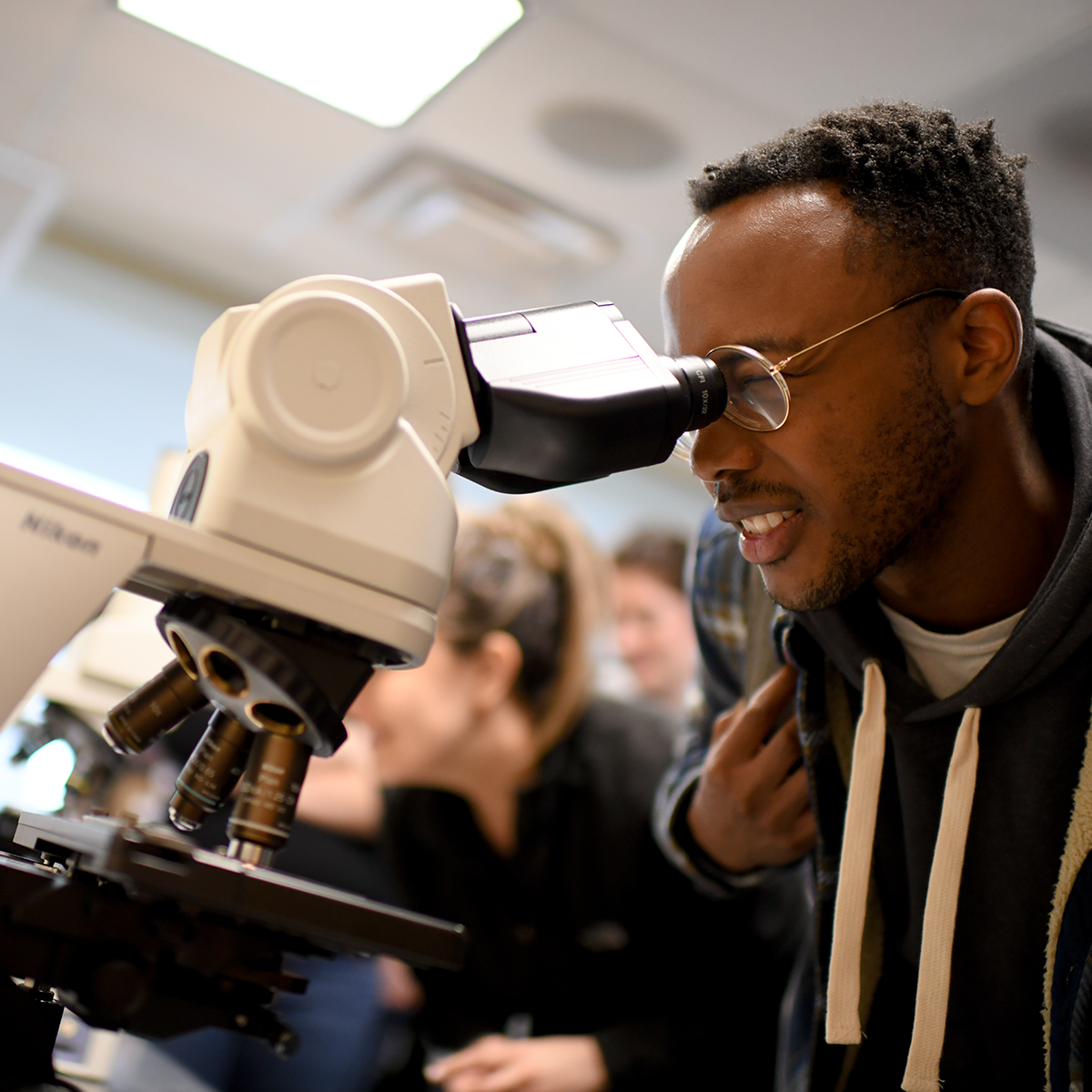 Student researcher reviews his research in the microscope