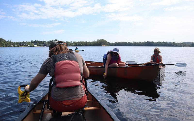 Tour participant (left) uses a Secchi disk to measure water clarity. Canoeist uses Secchi disk to measure water clarity on Lower Saint Regis Lake.