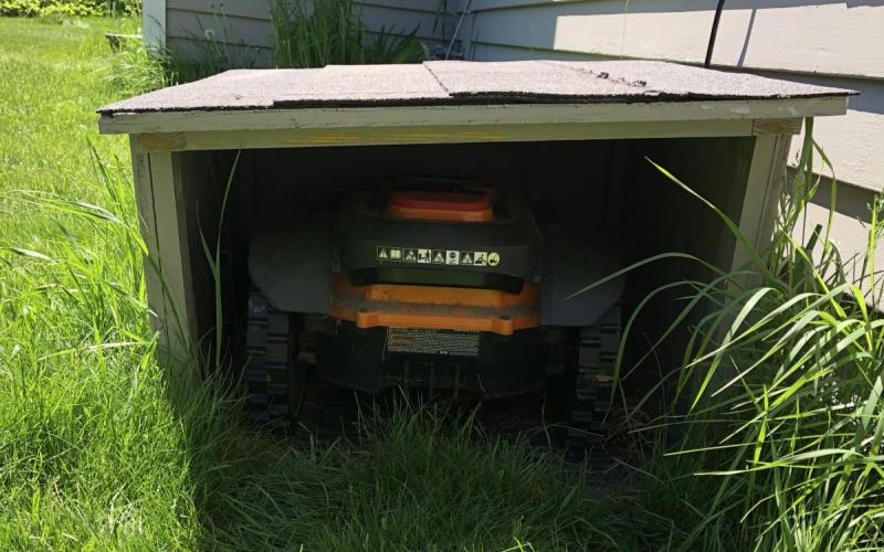 Mo, the robotic mower, inside his doghouse