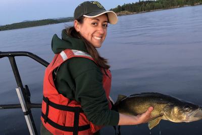Hannah Lachance holds fish on boat on lake