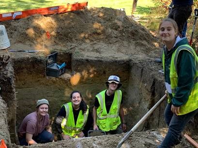 Anthropology students in a dig location hole