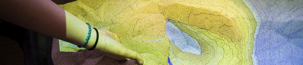 Image of someone digging into an augmented reality sandbox created by Rachel Seger '16.