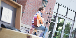 man playing a guitar on an outdoor stage