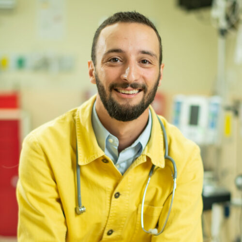 A pre-med student wearing a yellow shirt with a stethoscope