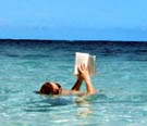 jane is floating on blue caribbean water reading