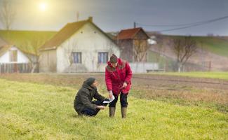 two people in a field reviewing a paper