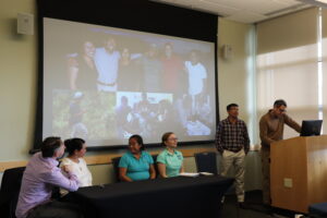 academic panel sits at a table while a man speaks