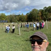Picture of a man with sunglasses and brown hat with a group of people in the background.
