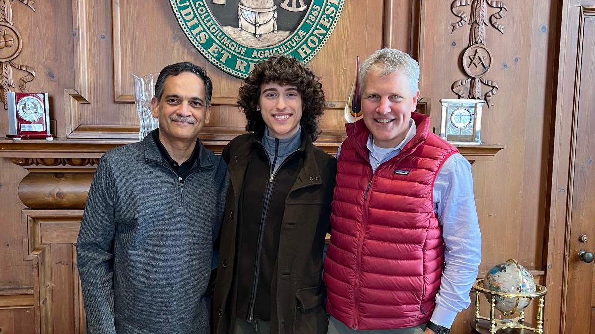 UVM President Suresh Garimella, Truman Scholar Zane Zupan, and dean of the Honors College David Jenemann standing in front of the fireplace in President Garimella's offie