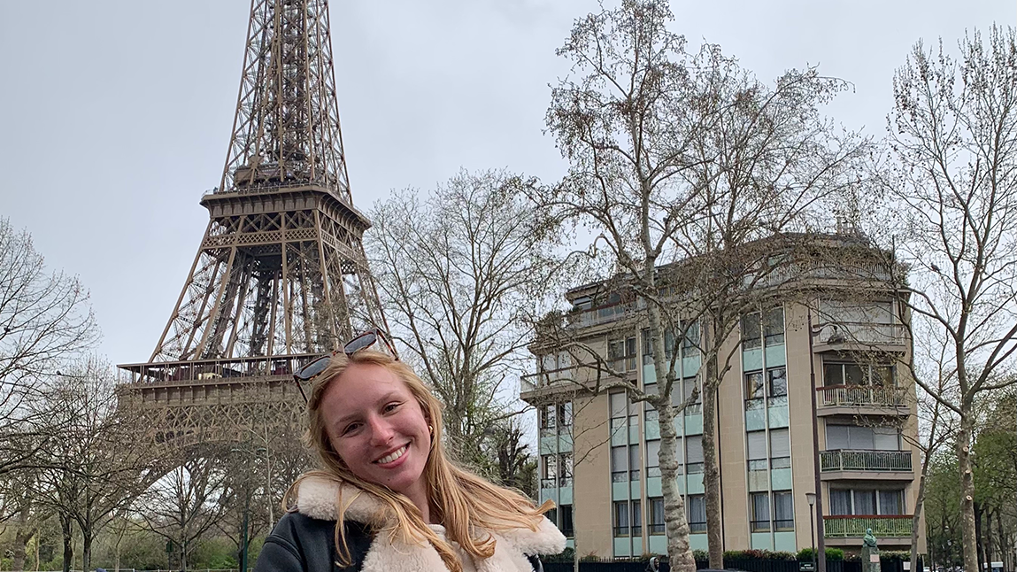 Young woman smiling in front of the eiffel tower in paris, france