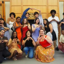 A group of students smiling and making heart shapes with their hands