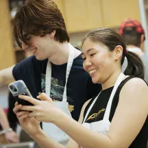 Two UVM students in a Jewish cooking class looking at a mobile phone