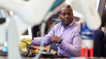 student looks at a robotic arm in the foreground