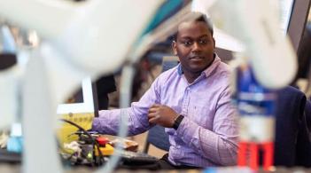 student looks at a robotic arm in the foreground