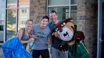 A white family during 2023 Fall move-in post for a photo with UVM mascot Rally Cat.