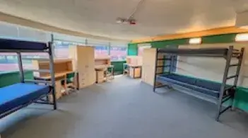 Residence hall room with four beds, four armoires/dressers, and four desks.r 