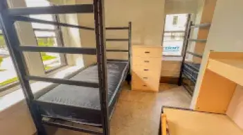 A residence hall room with two beds, two desks, two dressers, two wardrobes, and a wall divider.
