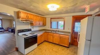 A kitchen with a stove, refrigerator, window, and cabinets. 