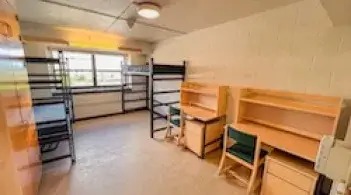 A room with two beds, two built-in closets, and two desks. 