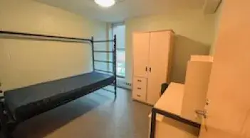 A room with a bed, dresser/closet, and desk. 