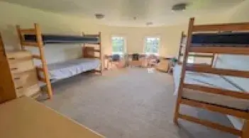 A room with four beds, four dressers/closets, and four desks.