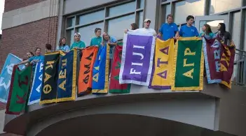 A variety of Fraternity and Sorority banners hanging from an overhang outside of the Davis Center