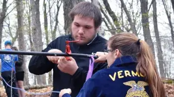 two students working on maple sap tubing outdoors