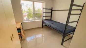 A room with one bed, one dresser/closet, and a desk. 