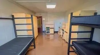 A room with three beds, three dressers, and three desks.