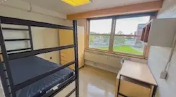 A room with one bed, a desk, and a closet. 