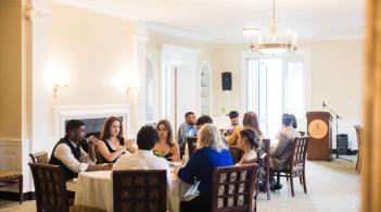 Student senators have a conversation at a banquet table in Waterman Manor.