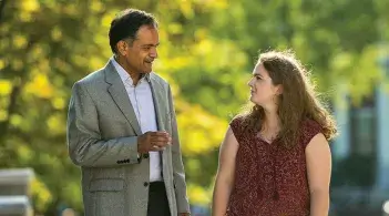 president garimella walks and talks with a student surrounded by trees
