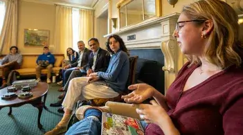 a student gestures with their hands while a room of observers listen intently