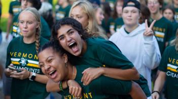 Two friends, one getting a piggy-back ride by the other, smile brightly for the camera at Convocation 2023