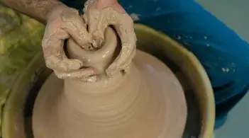 Student hands creating pottery on wheel