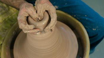 Student hands creating pottery on wheel