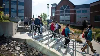 A group of students walk down stairs on their way to class.