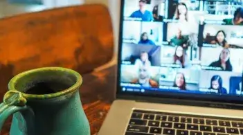 A coffee mug next to a laptop with a virtual meeting on the screen. Photo by Chris Montgomery.
