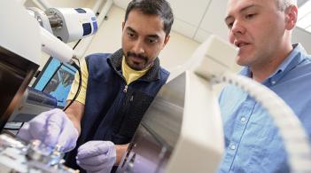 A graduate students works with Professor Matthew White on the electron microscope