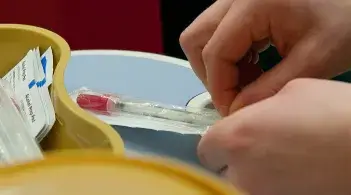 Hands opening a syringe
