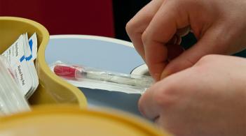 Hands opening a syringe