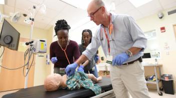 people looking at a human model on a surgical table