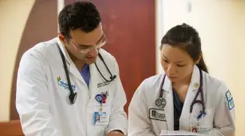 Two doctors, one masculine presenting and one feminine presenting, discussing patient care.