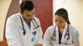 Two doctors, one masculine presenting and one feminine presenting, discussing patient care.