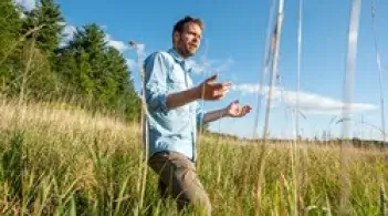 Faculty member Eric Roy standing in a swamp with his arms out gesturing