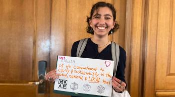 student holding sign in front of wall