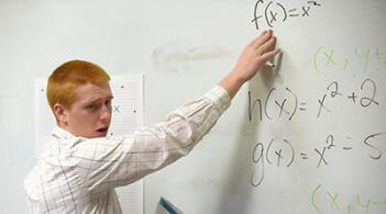 Student teacher explains an equation at a whiteboard