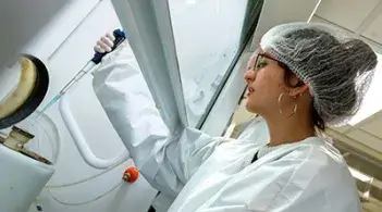 Undergraduate student researcher takes a sample in a physics clean room.