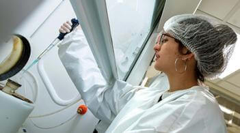 Undergraduate student researcher takes a sample in a physics clean room.