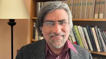 A person seating in front of a bookcase filled with various books